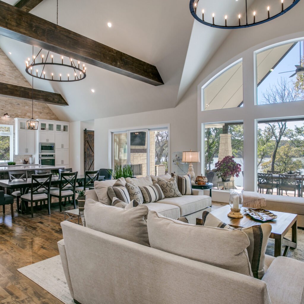 Open living, dining and kitchen space with exposed beams and tall windows