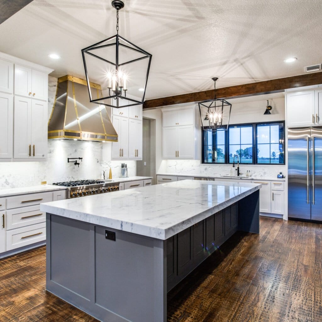 Custom kitchen with white cabinetry, a dark island and exposed ceiling beams