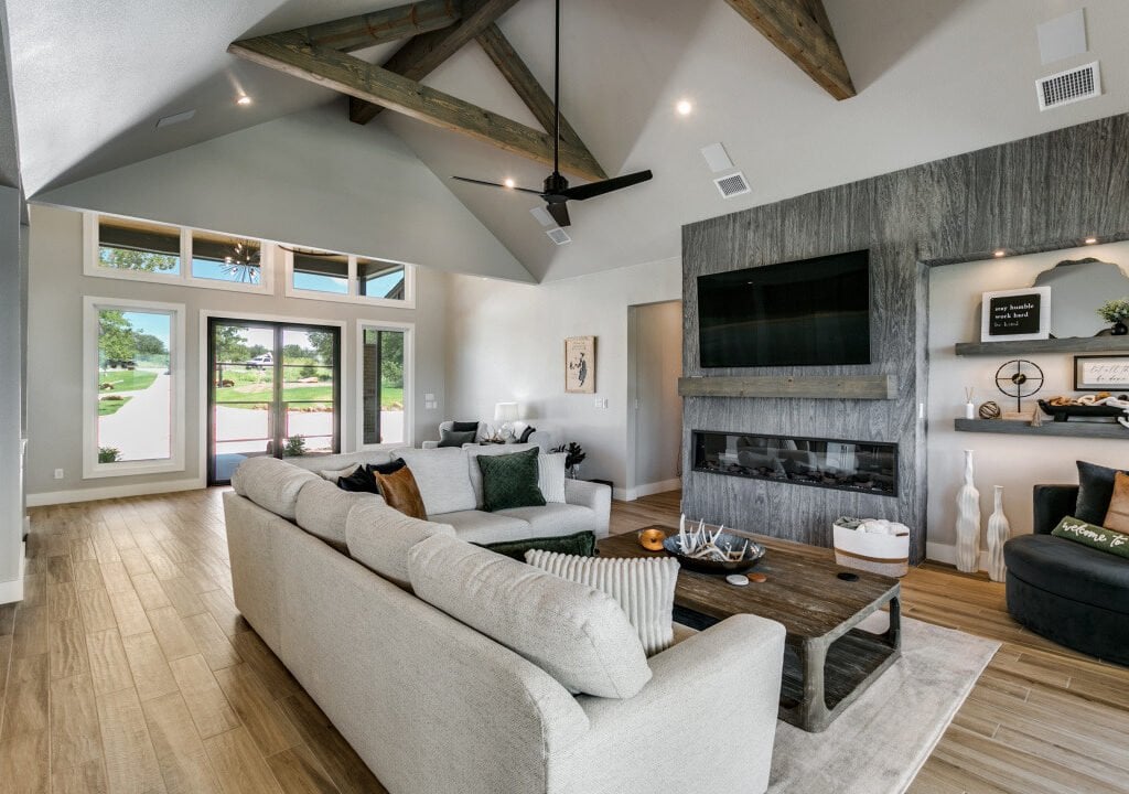 Great room with exposed roof beams, a linear fireplace and garden views