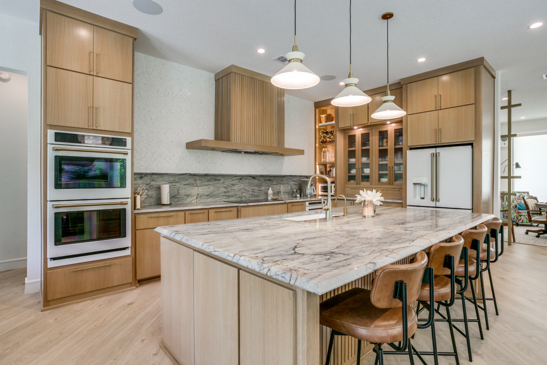 Light wood kitchen with a stone island and pendant lighting in an Edge Crew custom home