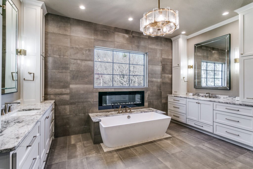 Primary bathroom with a freestanding tub, fireplace and twin vanities