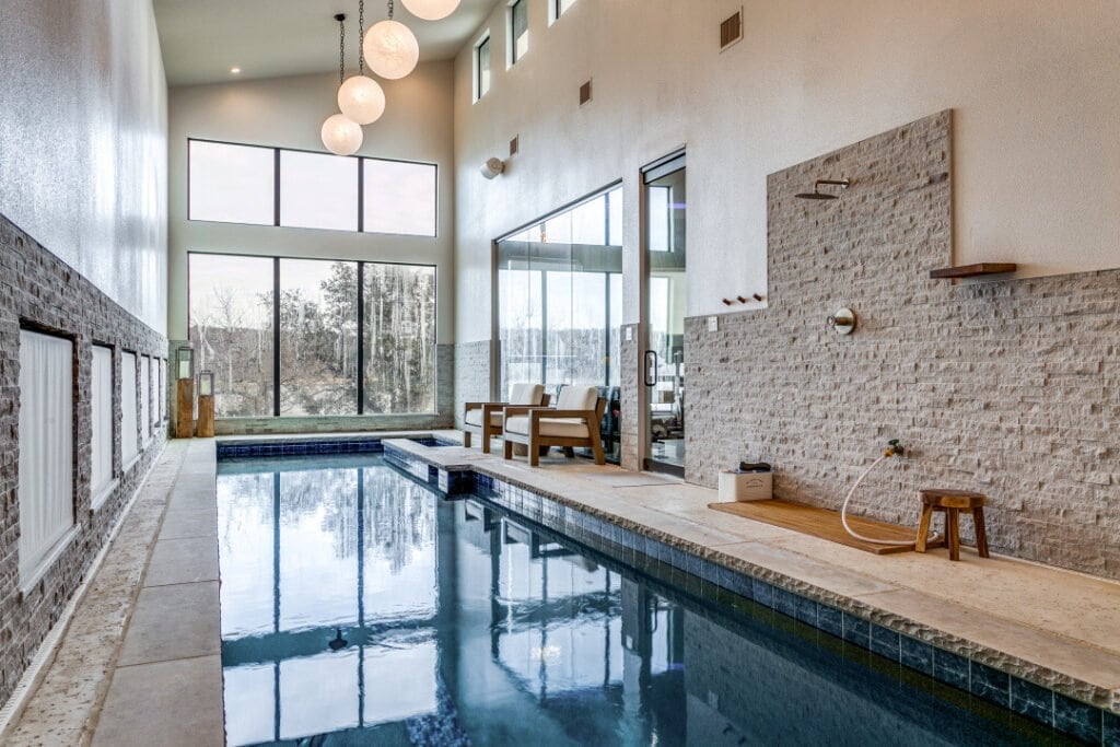 Indoor pool with tall windows and stone accent wall at El Regalo