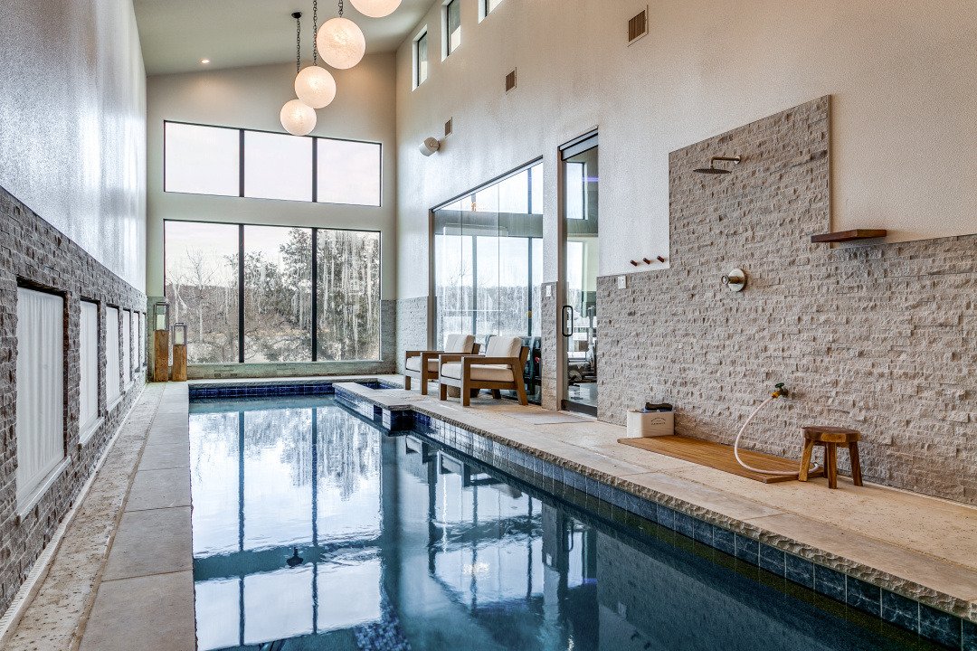 Indoor pool with tall windows and stone accent wall at El Regalo